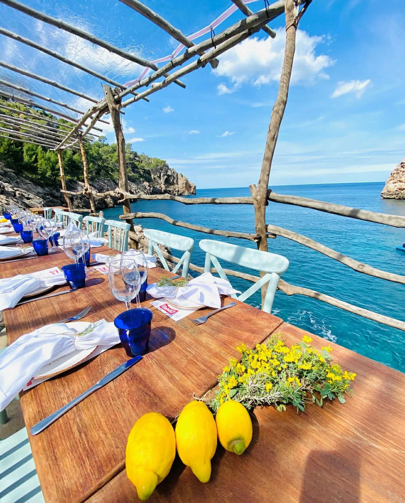 Outdoor dining setup with lemons on a wooden table by the sea