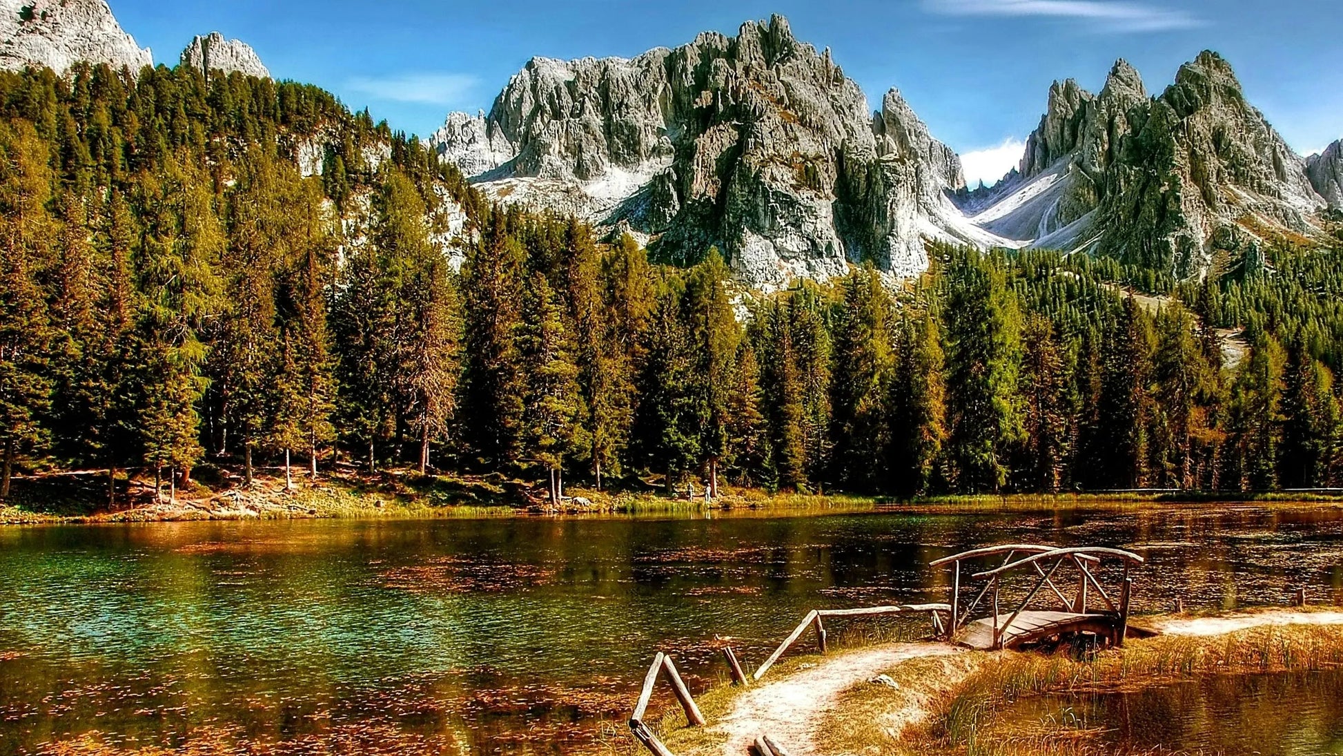 Lake surrounded by mountains and trees with a wooden dock.