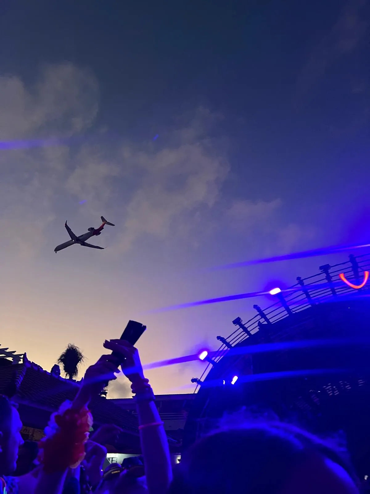 Airplane flying in a purple sky with a crowd below