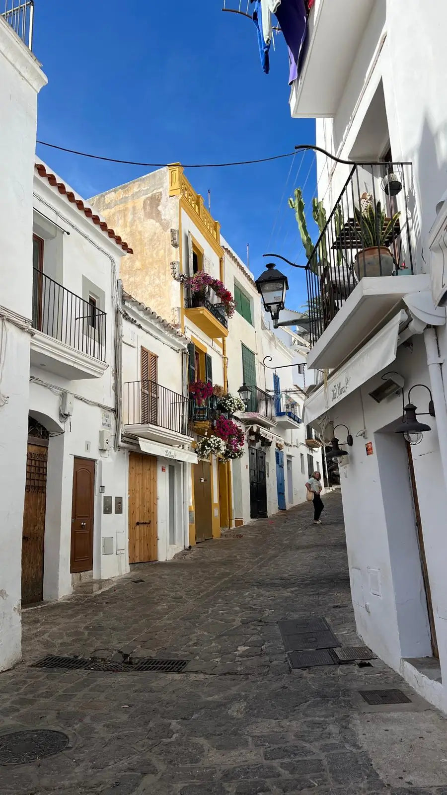 narrow street in a Mediterranean town with white buildings and blue sky