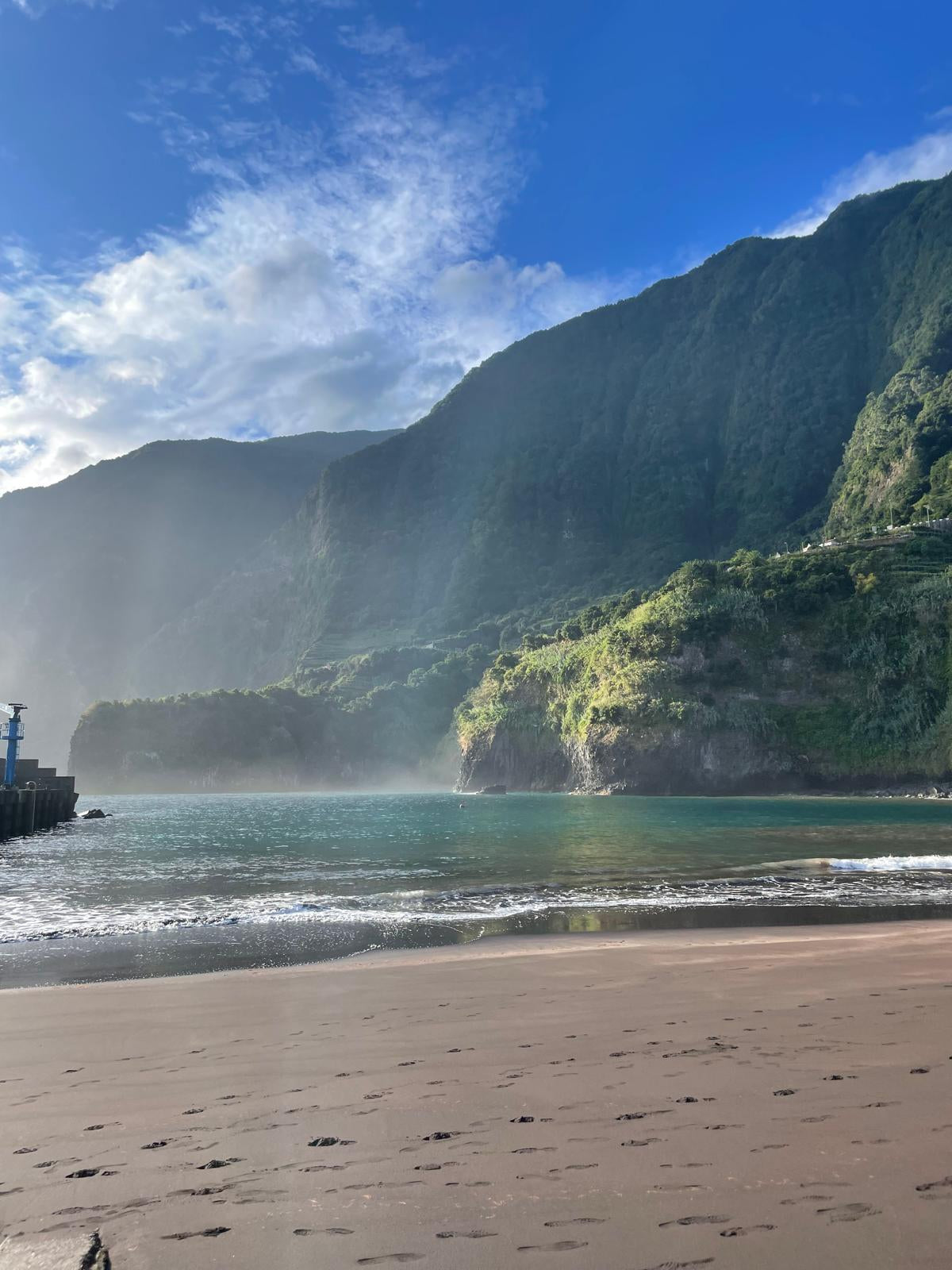 Beach with ocean waves, mountains, and clear sky