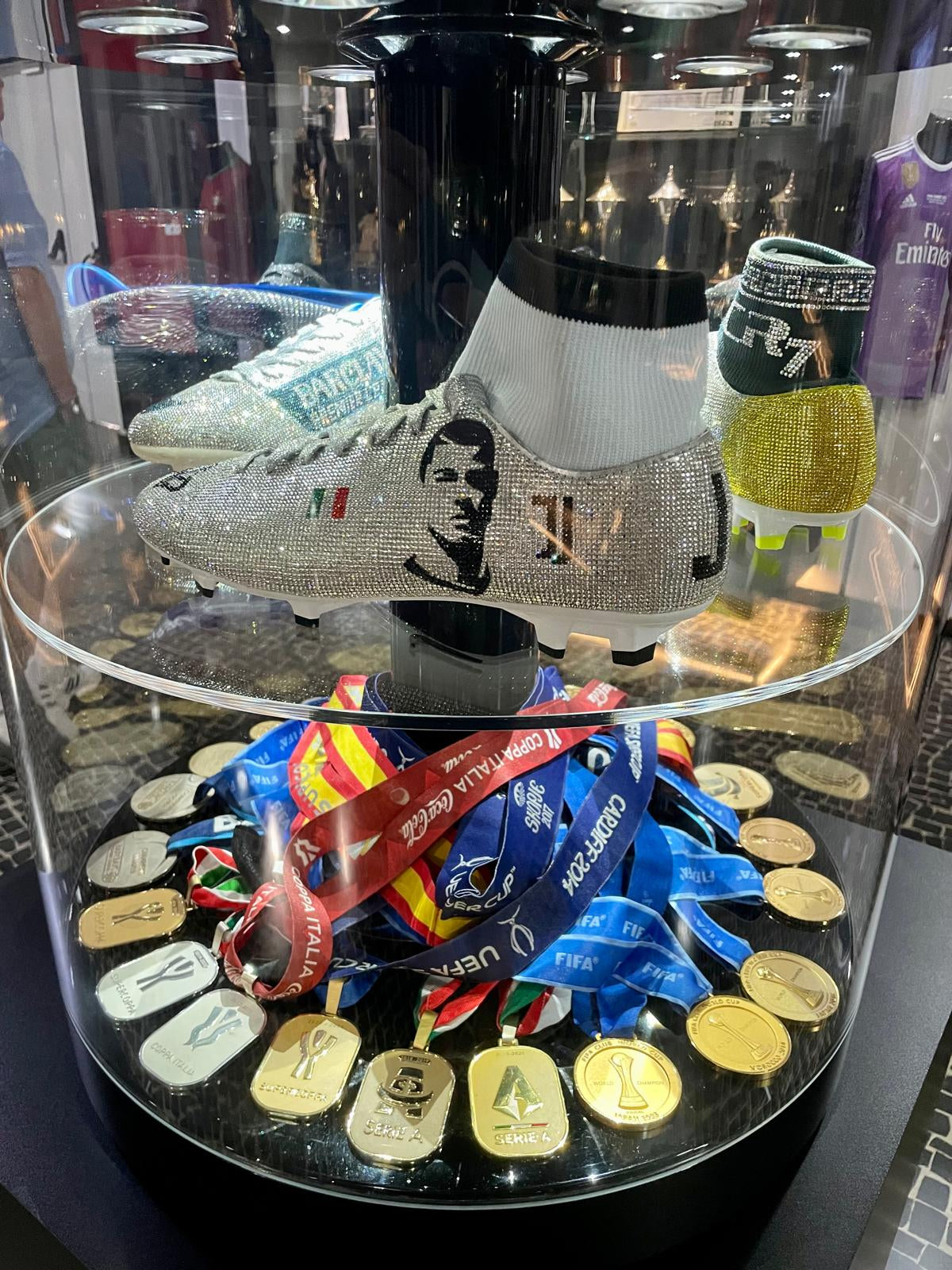 Shoe with rhinestone detailing on a glass display case with medals and ribbons.