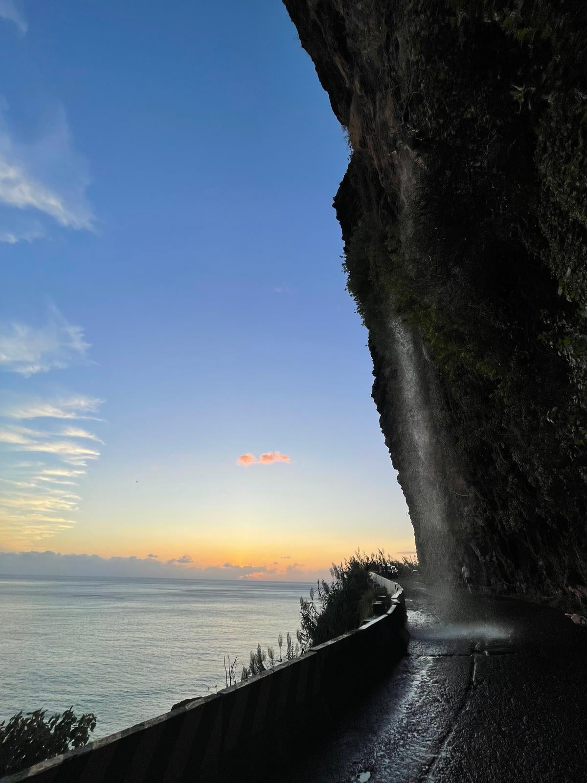 Sunset over the ocean viewed from behind a rocky outcrop