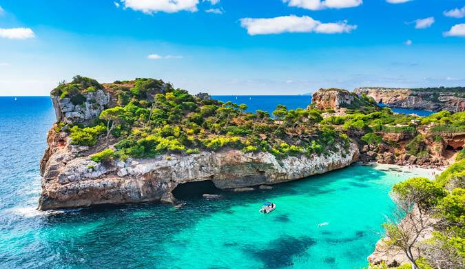 Scenic view of a rocky island with clear blue water and a blue sky.