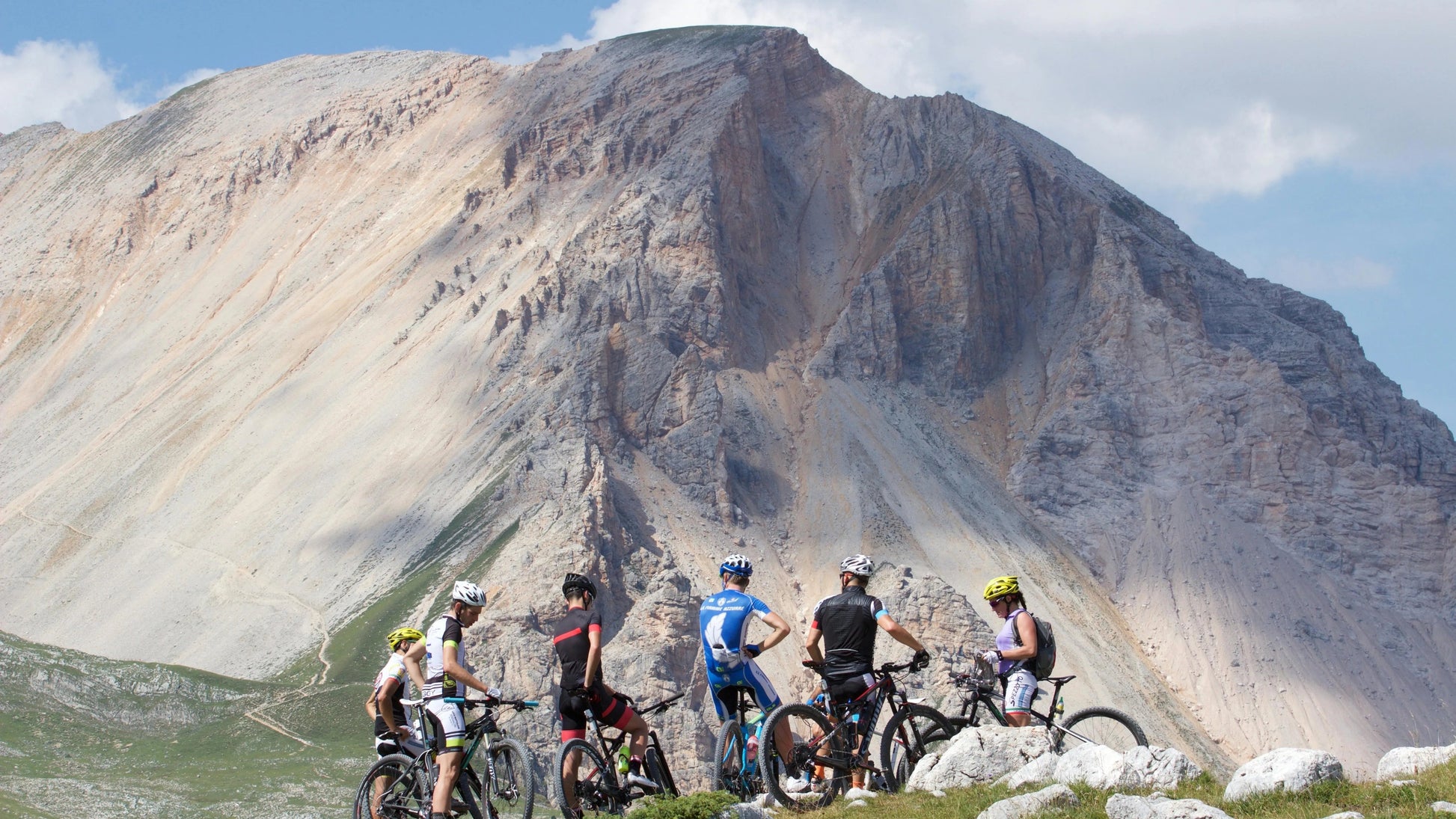Group of mountain bikers on a rocky outcrop with a mountainous landscape in the background