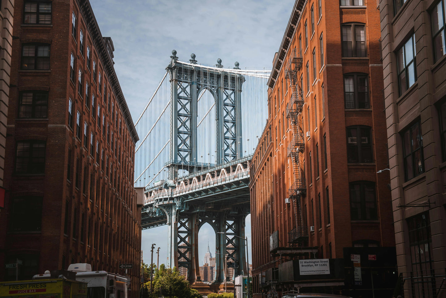 Manhattan Bridge viewed between two brick buildings in an urban setting