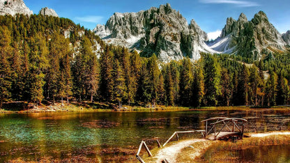 Lake surrounded by mountains and trees with a wooden dock.