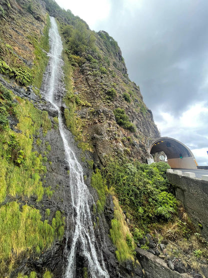 Waterfall cascading down a rocky cliff with a building in the background