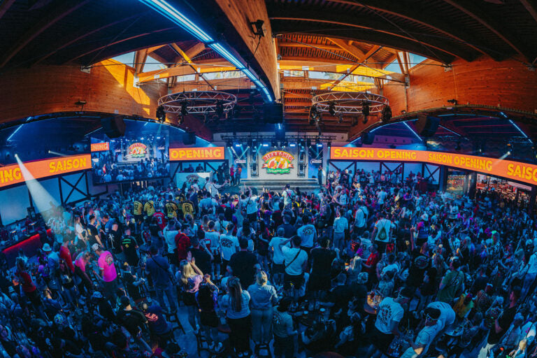 Large indoor event with a crowd and illuminated signs, likely a concert or festival.