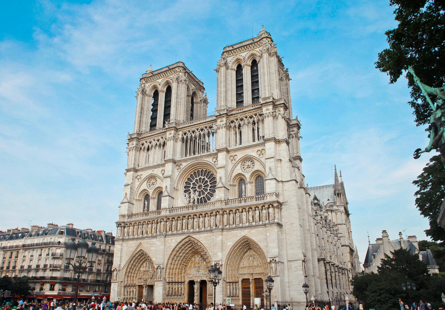 Cathedral with tall towers and a large rose window under a blue sky.
