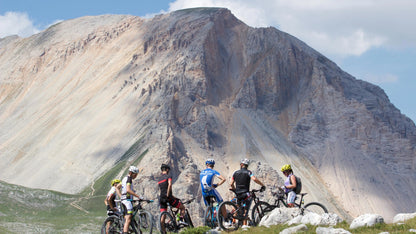 Group of mountain bikers on a rocky outcrop with a mountainous landscape in the background