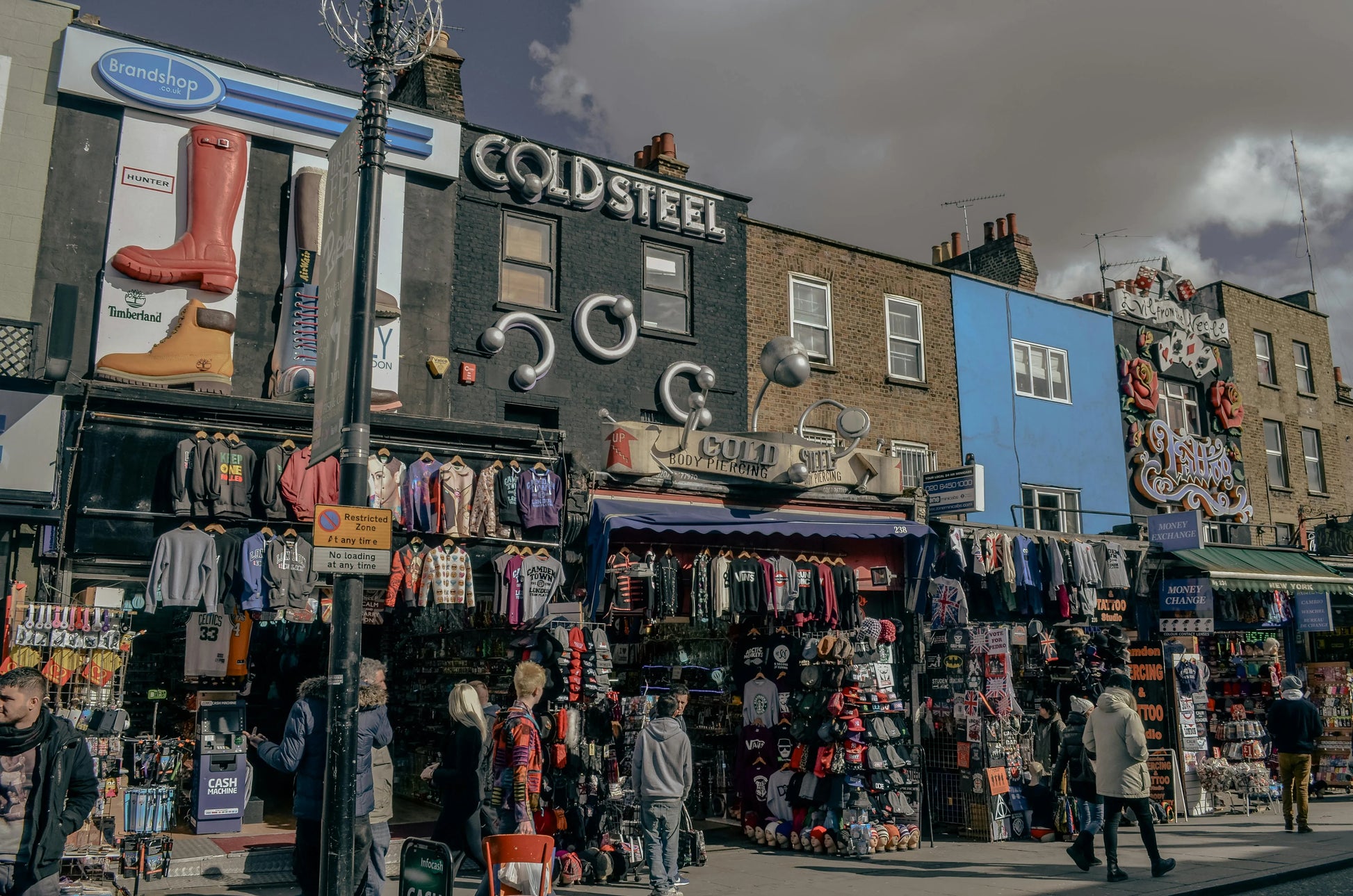 Street scene with a clothing store named 'Cold Steel' and people walking by.