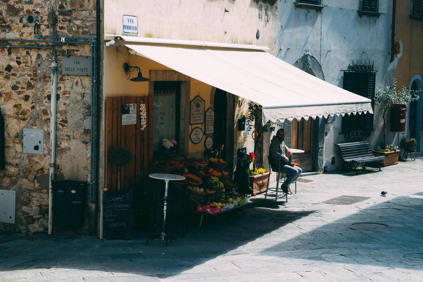 Street scene with a small shop and outdoor seating area in an urban setting