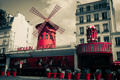 Red windmill structure with 'Moulin Rouge' sign against a gray sky.