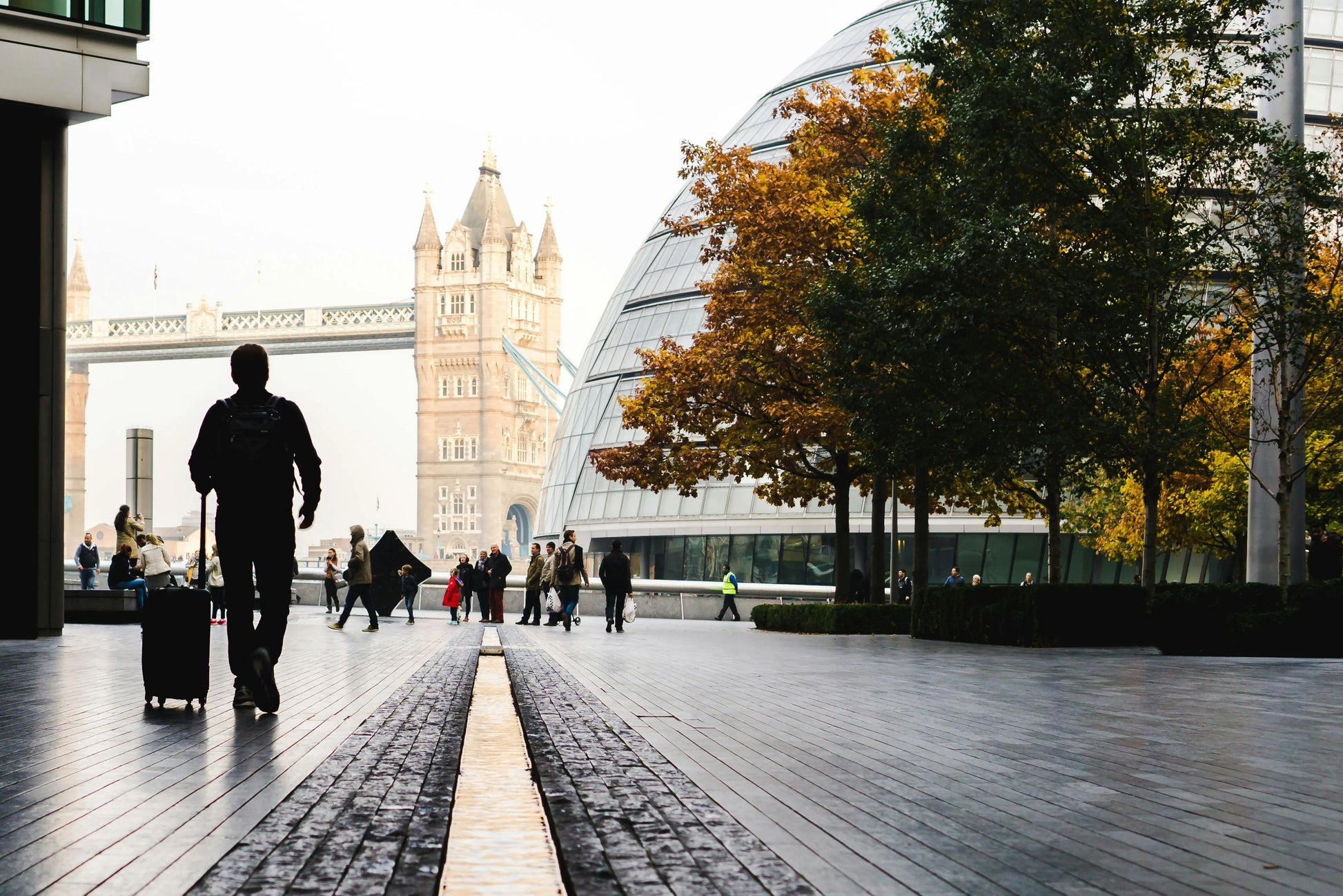 Person with a suitcase walking on a city street with a clock tower in the background