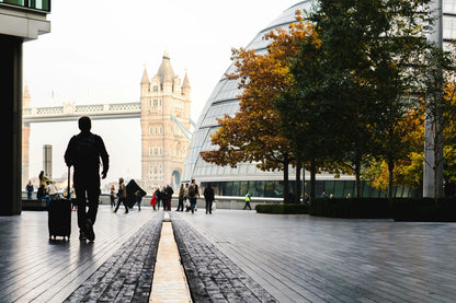 Person with a suitcase walking on a city street with a clock tower in the background