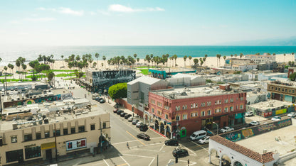 Aerial view of a coastal cityscape with buildings, roads, and ocean in the background.